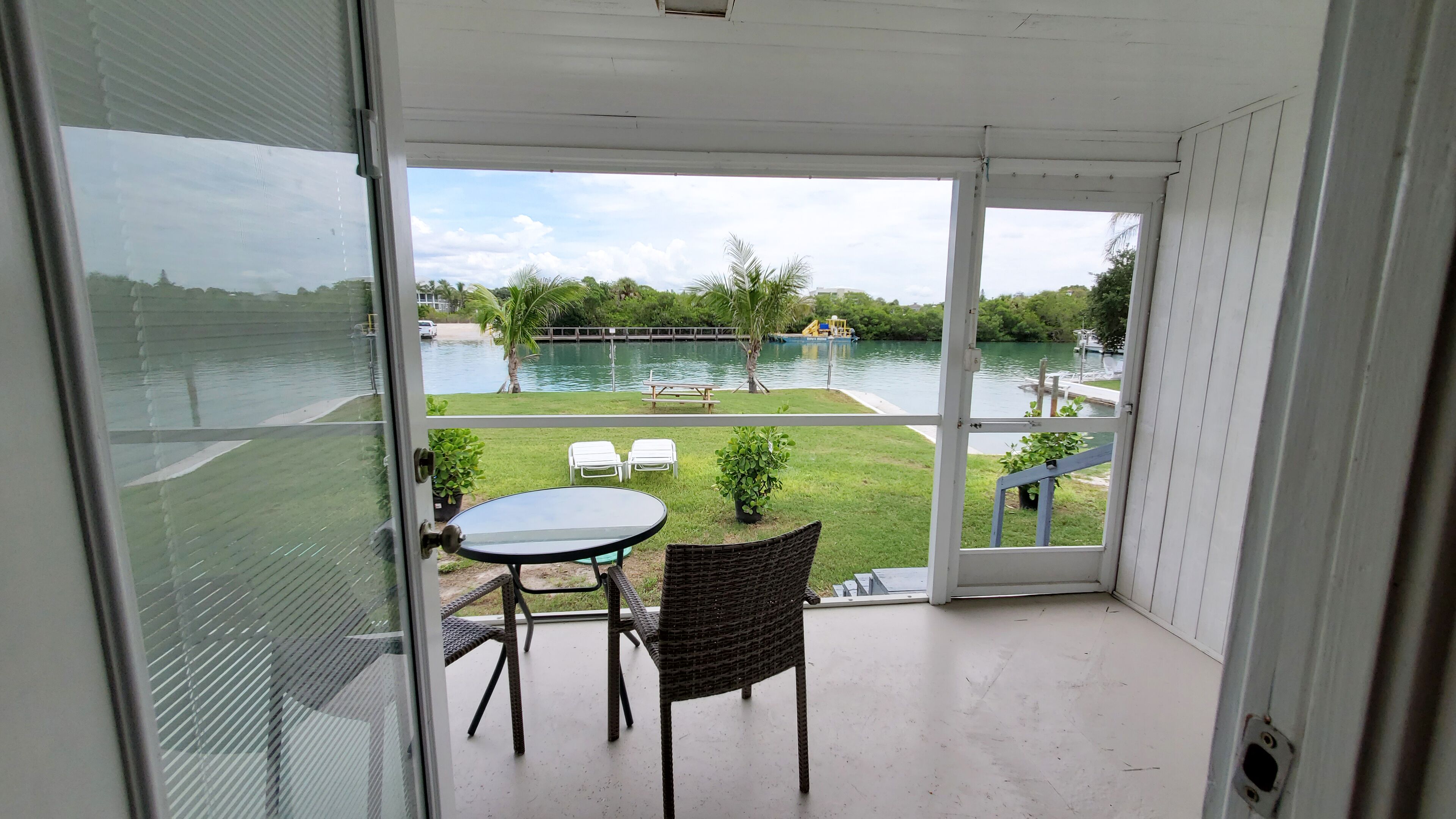 A balcony with a glass door, a small table, and two wicker chairs.
