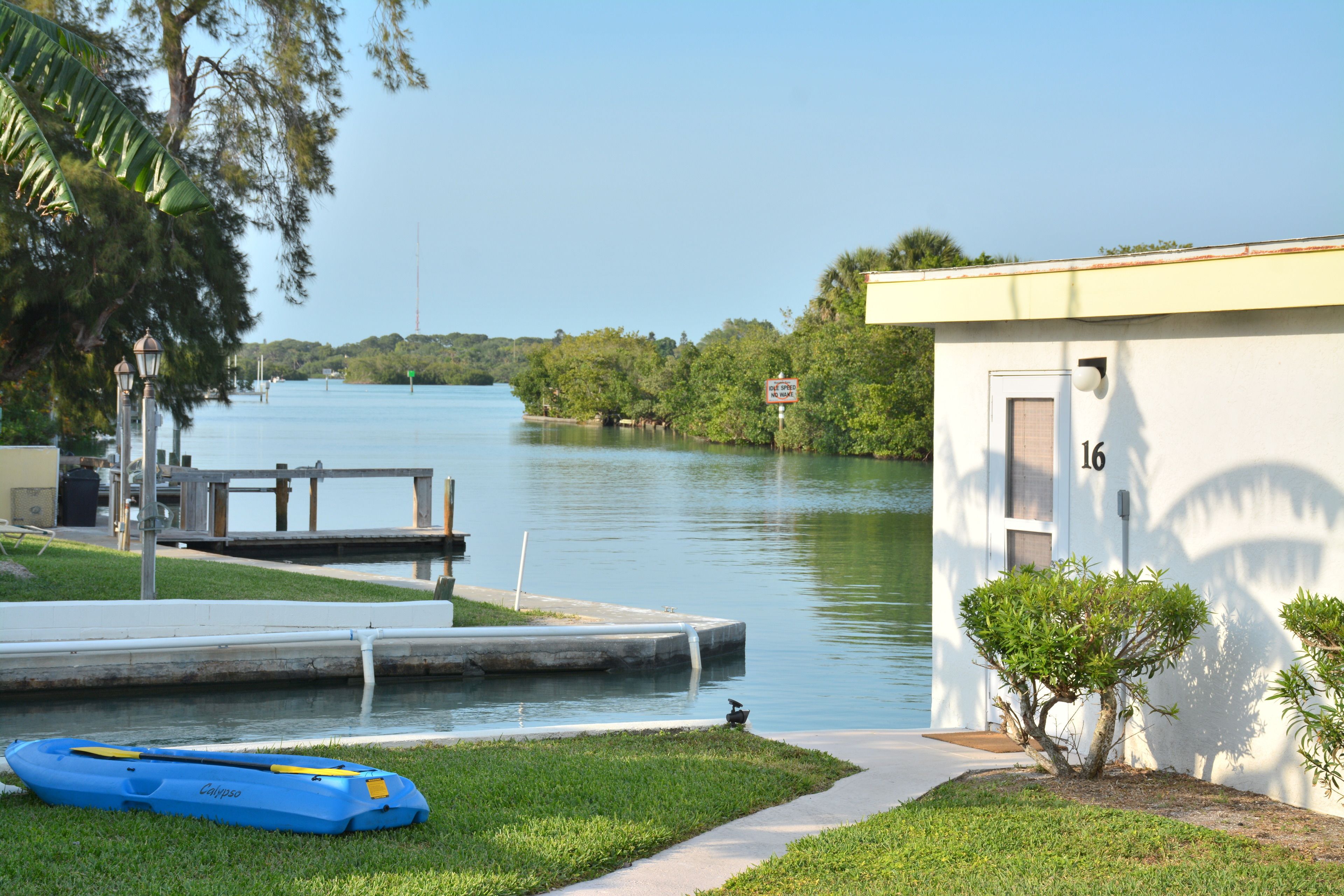 A riverside view with a dock, a kayak, and a small building with the number 16.