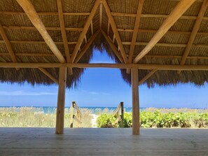 Una estructura de madera con techo de paja que da a una playa.