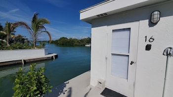 A well-maintained lawn with a patio area, outdoor seating, and a white building with multiple doors. at Casey Key Resort 