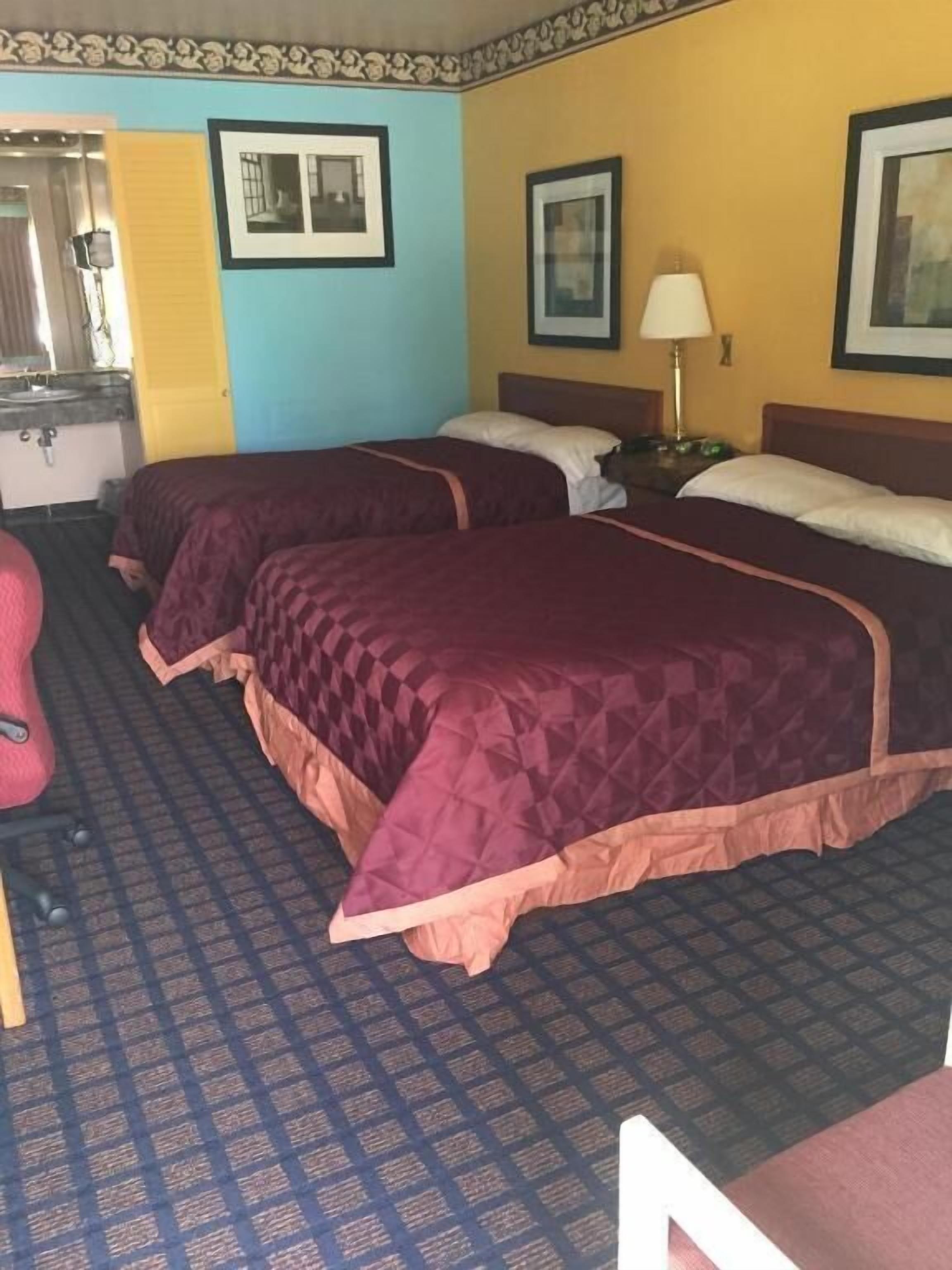A hotel room with two beds, a bathroom, and a mirror.