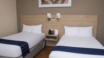 Habitación de hotel con dos camas, cabecera de madera, mesita de noche con teléfono y lámpara, y un cuadro en la pared.