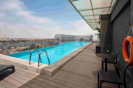 Una piscina al aire libre, sillones reclinables de piscina
