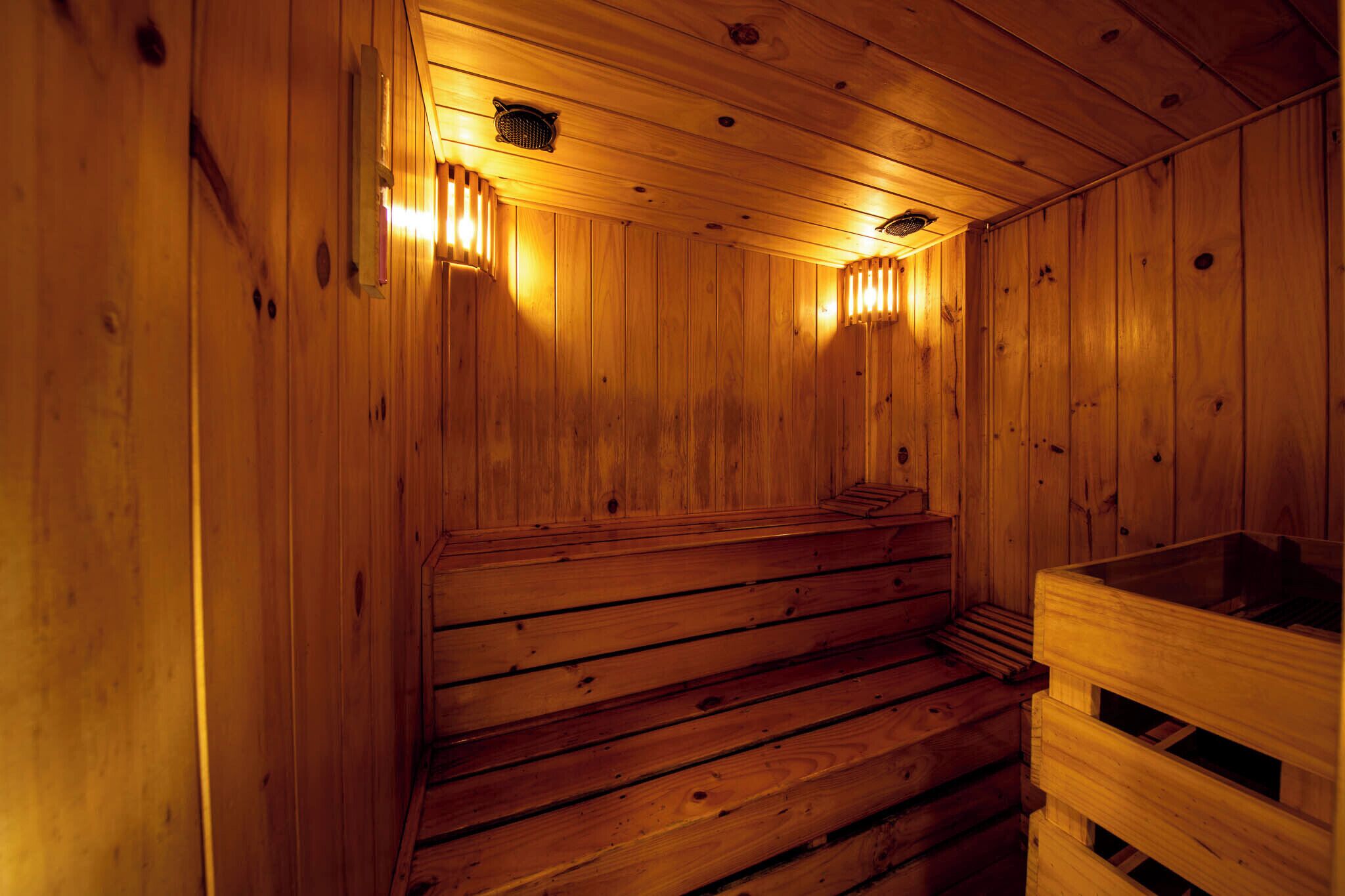 A wooden sauna with benches and a wooden bench on the right.