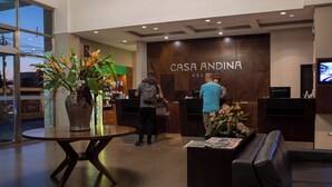 A hotel reception area with a modern design, featuring a reception desk, a seating area, and a large window providing a view of the cityscape. - Casa Andina Select Tacna (Tacna)