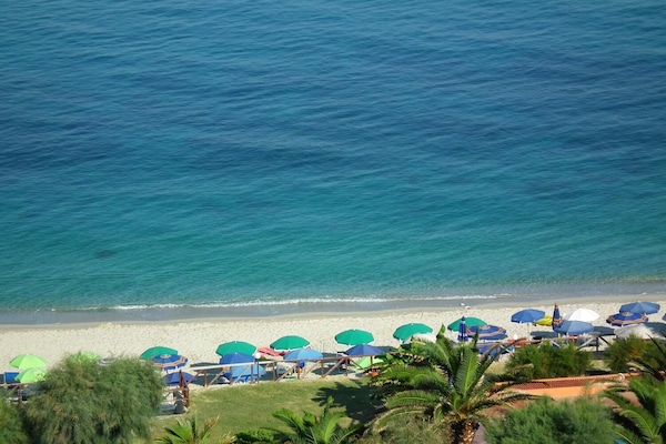 Privat strand, hvit sand, solsenger og parasoller