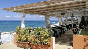 Een terras met tafels en stoelen, met uitzicht op de oceaan.