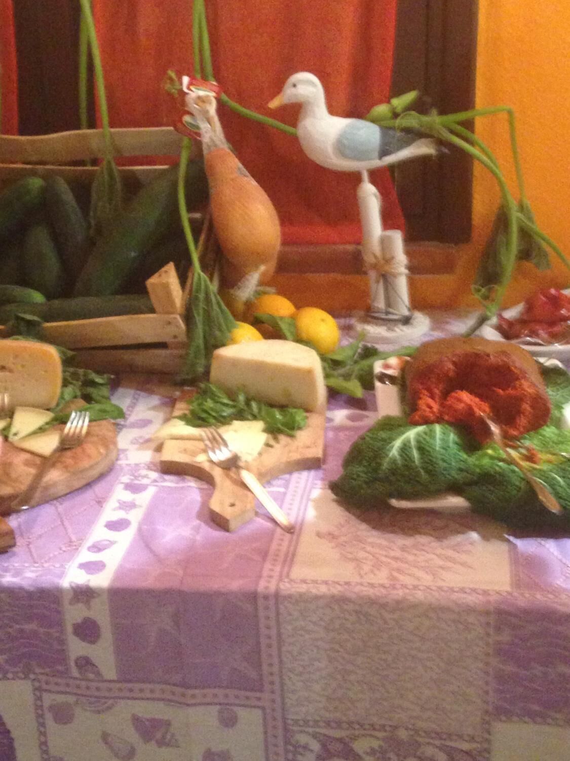 A table with various food items and utensils, including cheese, vegetables, and a bird figurine.