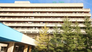 Un edificio de varios pisos con balcones, un cartel con la leyenda 'HOTEL POMPEUZA' en la parte superior y árboles en primer plano.