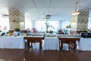 Disposição de buffet com várias estações de serviço, uma janela ampla que oferece luz natural e um teto com padrão de grade.