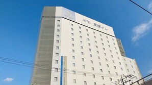 A tall, white hotel building with multiple windows and a sign indicating it is a hotel.
