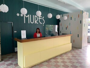 A reception desk with a sign reading 'MURES' and decorative paper spheres hanging above. - Mures Saturn (Saturn)