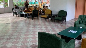 A spacious indoor area with a checkered floor, multiple seating options including a yellow sofa, green armchairs, and a black table. - Mures Saturn (Saturn)