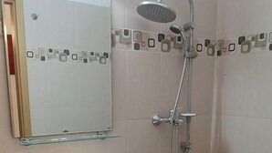 A bathroom with a white sink, a glass shelf above it, a shower with a handheld showerhead, and a toilet. - Mures Saturn (Saturn)