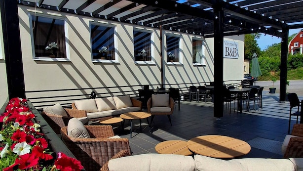 An outdoor seating area with wicker furniture, a covered patio, and a sign for Vimmerby B&B.