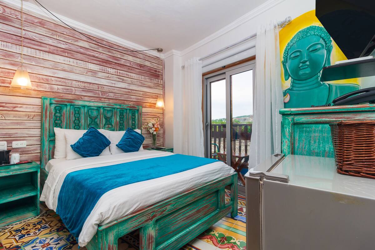 A bed with a blue and white bedspread, a green headboard, and a nightstand with a lamp.