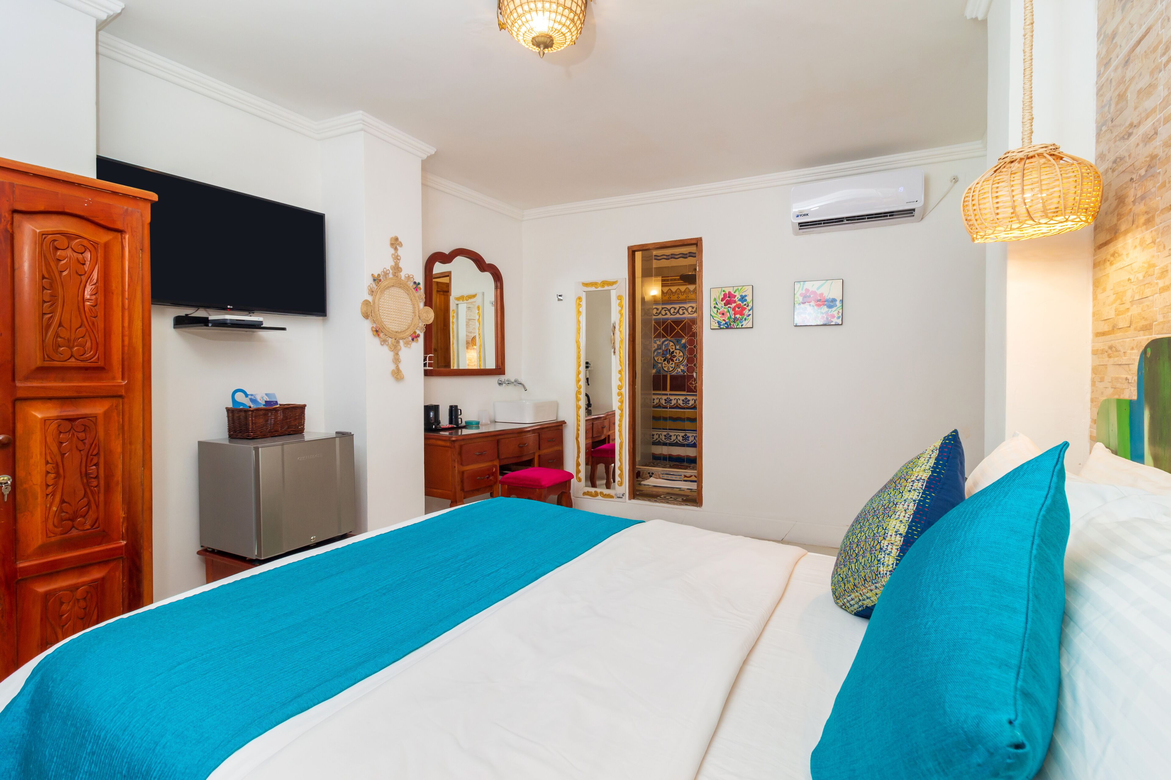 Una habitación de hotel con cama, televisión, armario, escritorio y espejo.