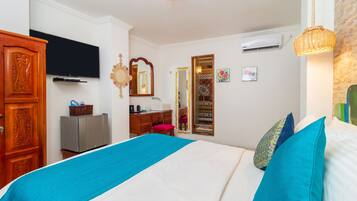 Una habitación de hotel con cama, televisión, armario, escritorio y espejo.