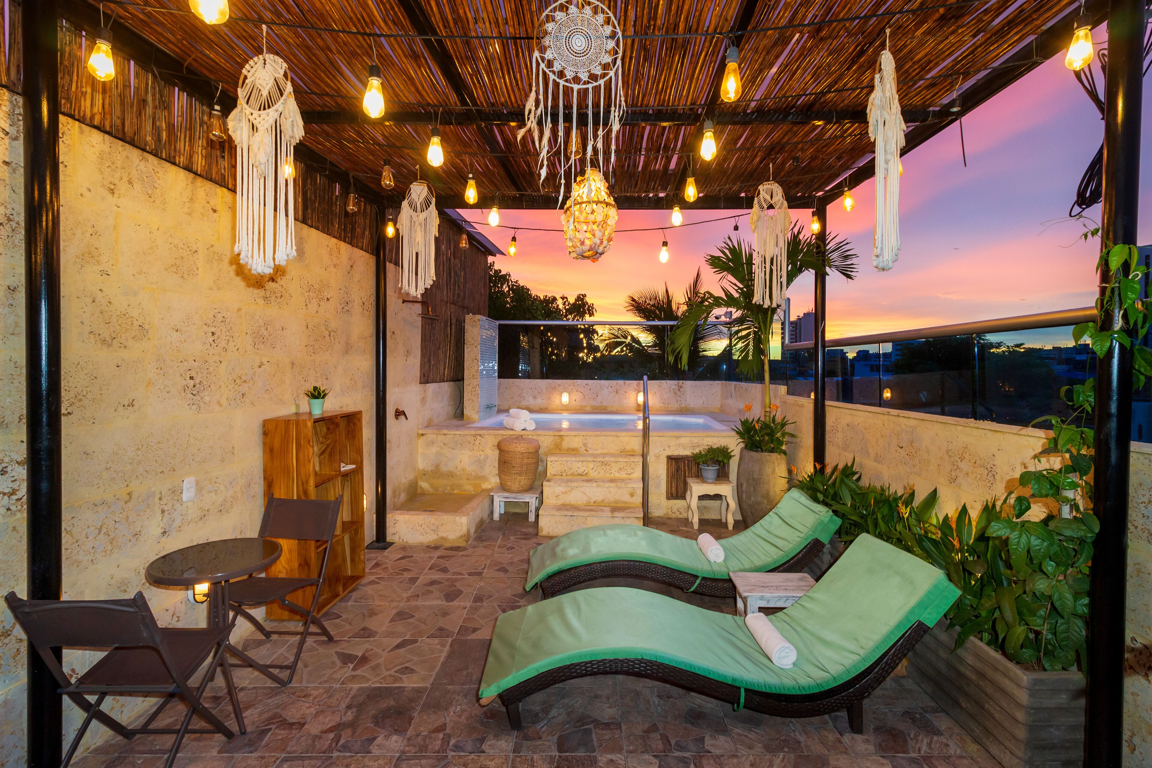 Una terraza en la azotea con dos sillones, una mesita y un jacuzzi.