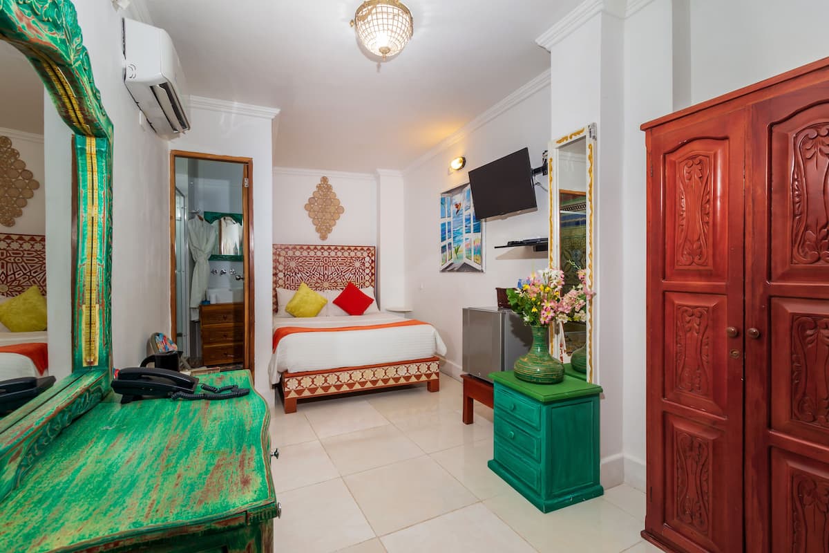 A hotel room with a bed, a TV, a dresser, and a wardrobe.