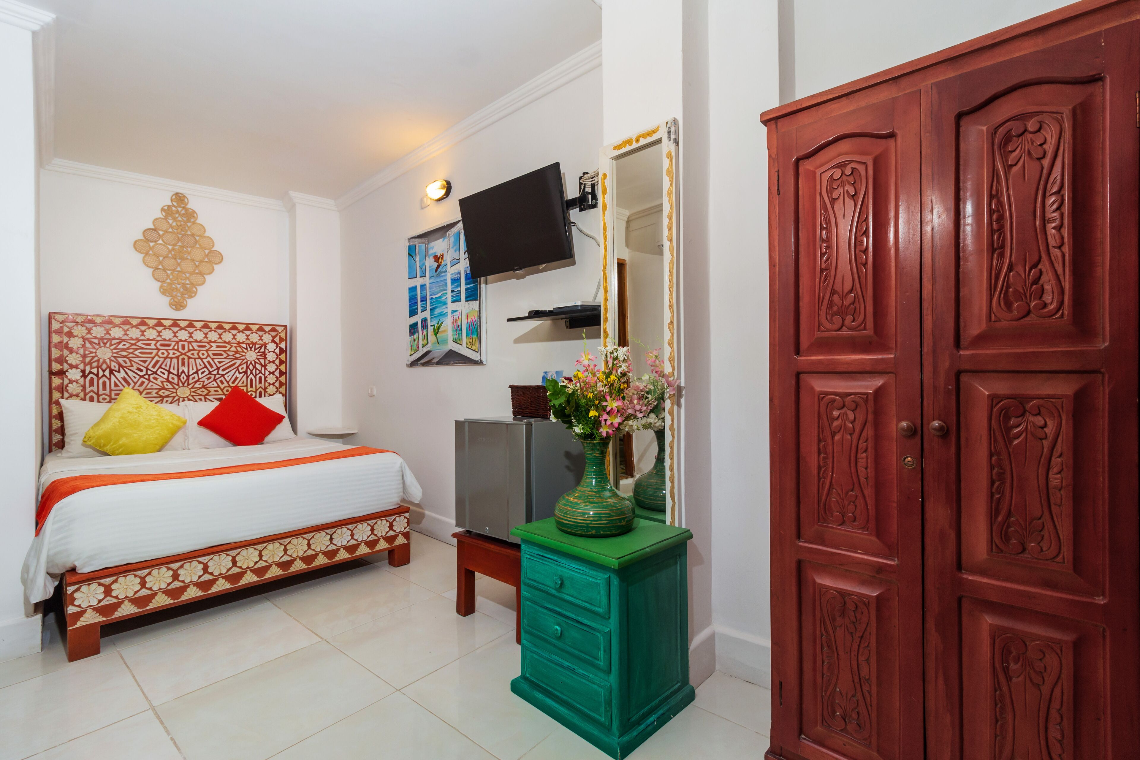 A bedroom with a bed, a TV, a dresser, and a wardrobe.