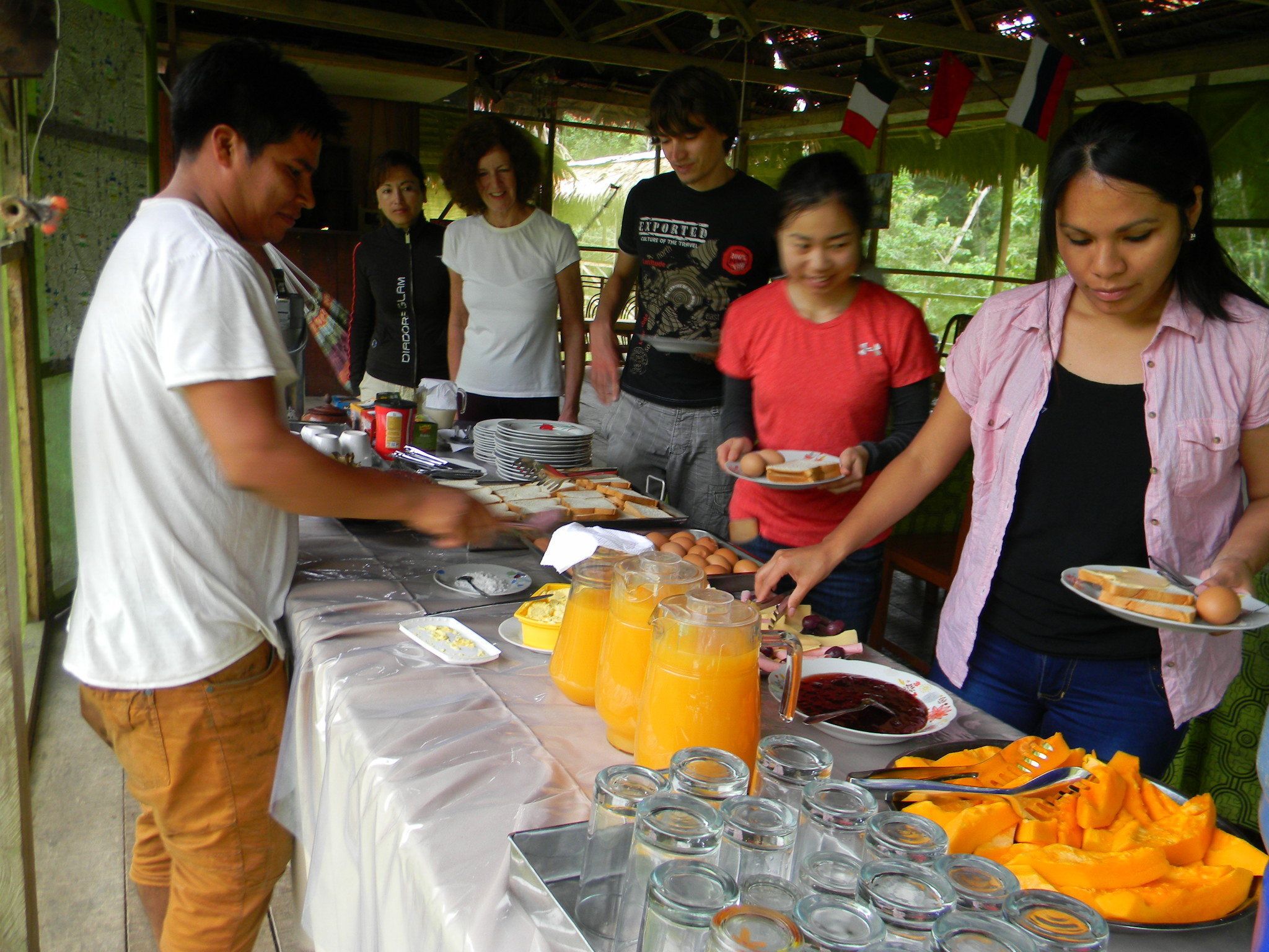 A buffet table with various food items and drinks, surrounded by people serving themselves.