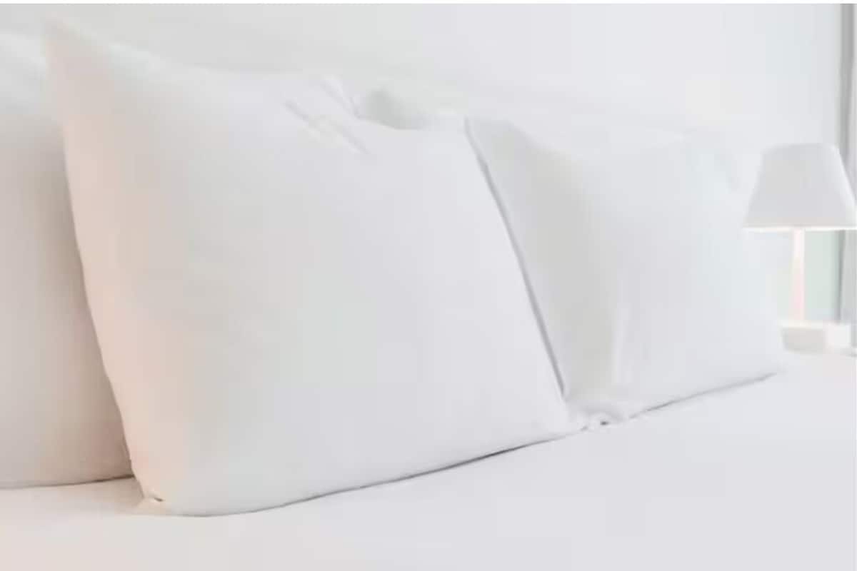 A bed with white bedding and pillows.