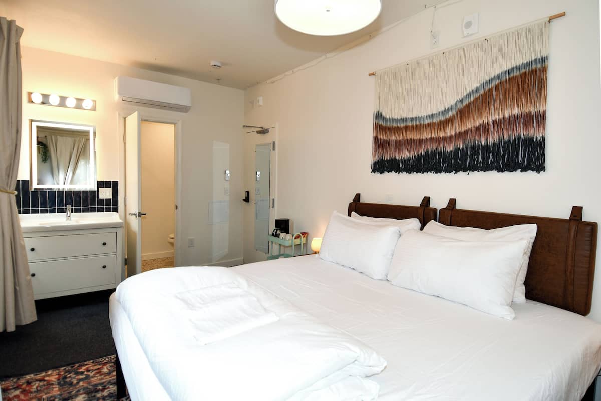 Ein Hotelzimmer mit einem großen Bett, einem Nachttisch, einem Spiegel und einem Wandbild.