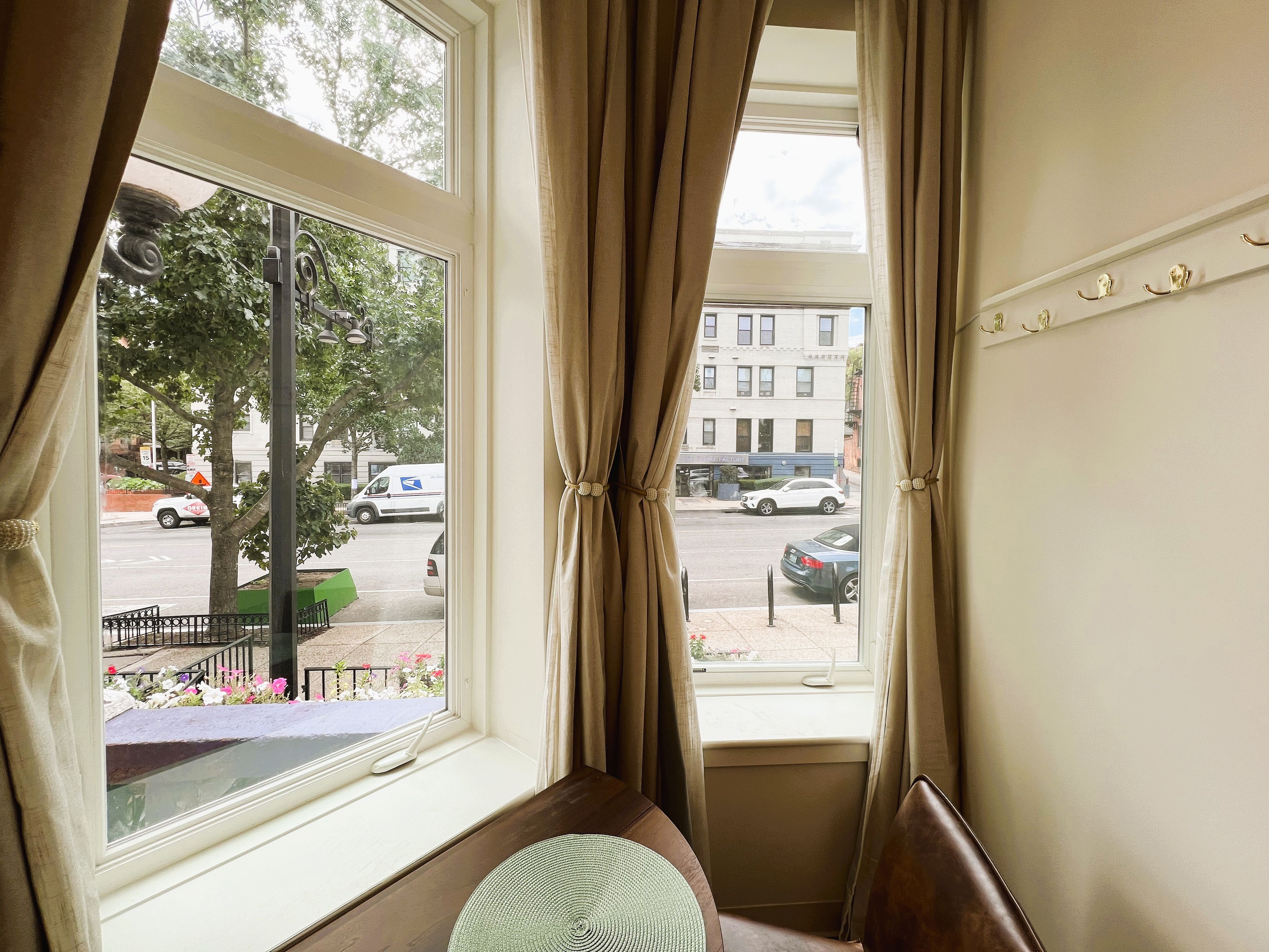 A room with a large window, a view of the street, and a bench.