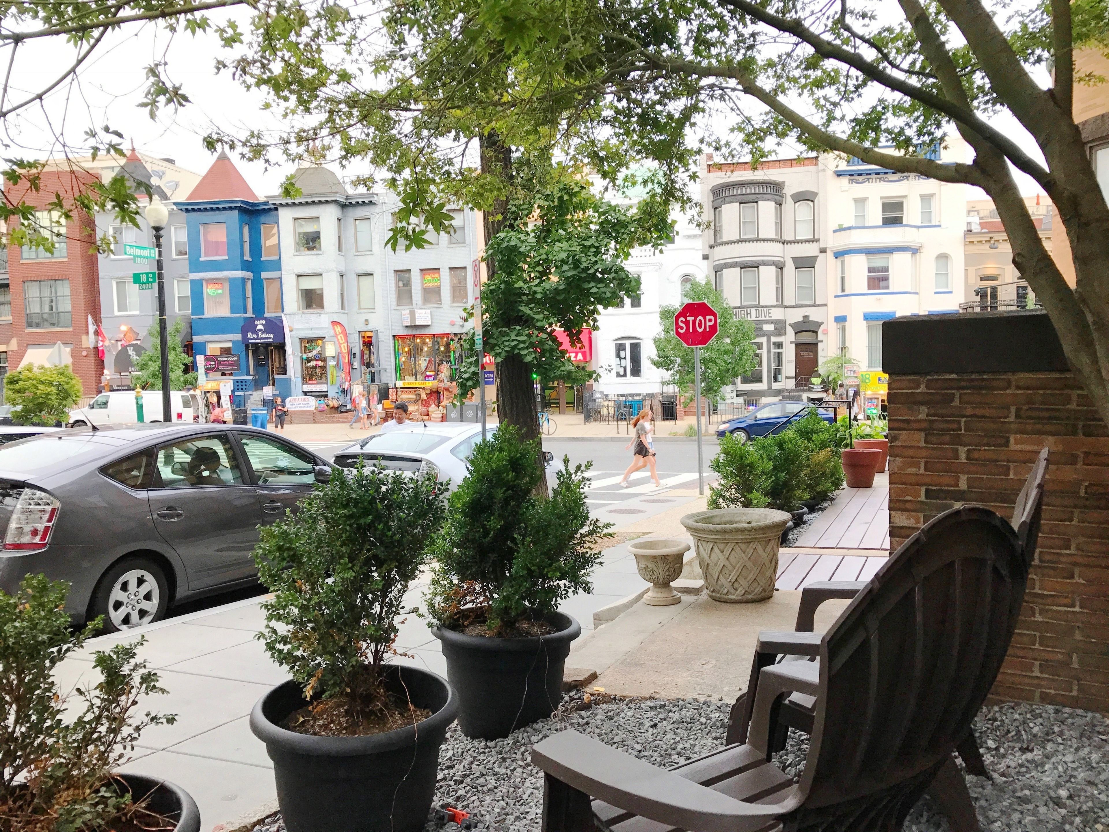 Une vue d’une rue avec un banc, des plantes en pot et un panneau de signalisation indiquant un arrêt.