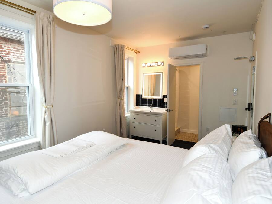 Habitación de hotel con una cama grande, una tocador con espejo y un ventanal con cortinas.
