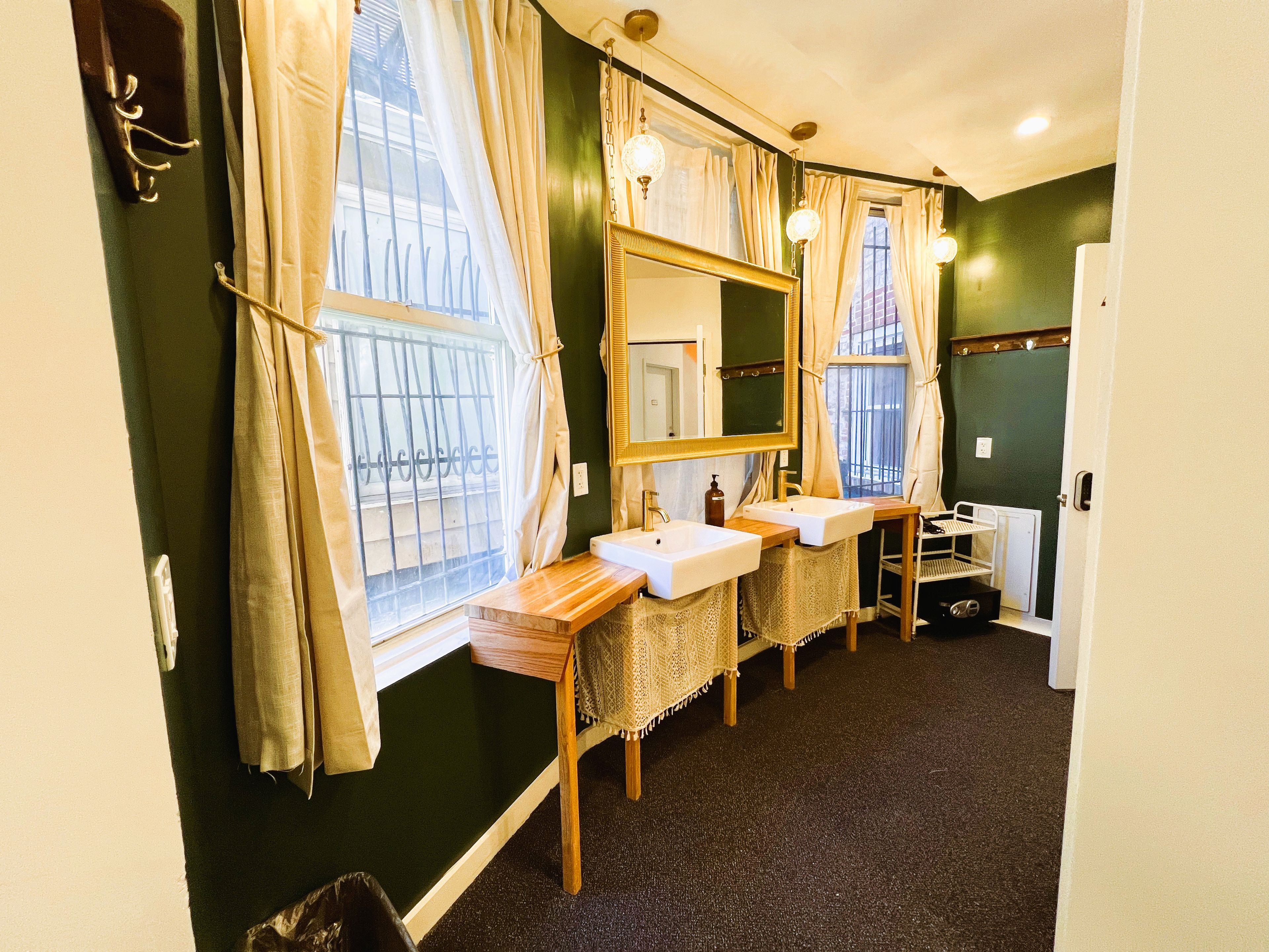 A bathroom with two sinks, a mirror, and a window with curtains.