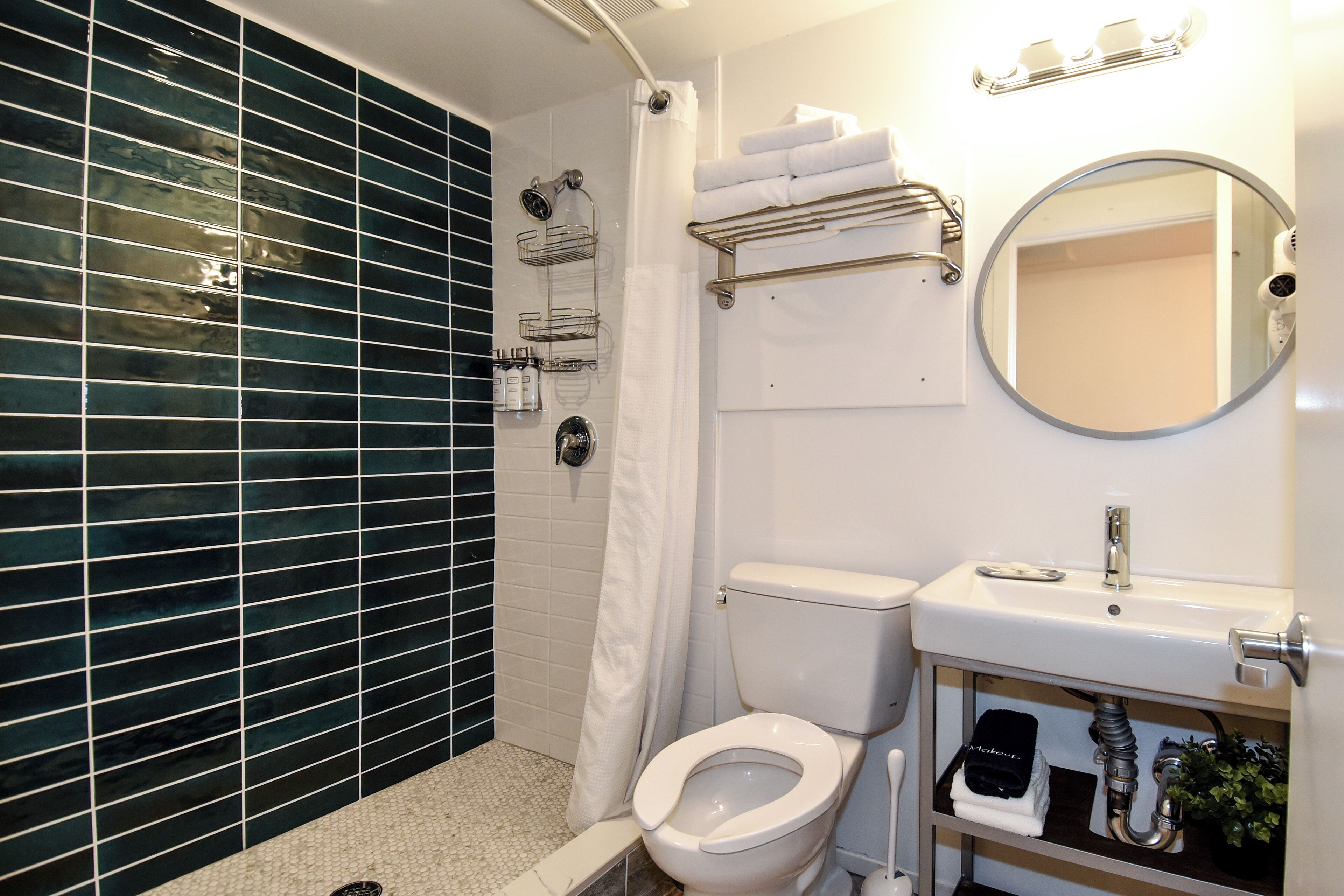 A bathroom with a white toilet, a sink with a mirror, and a shower area with a glass door.