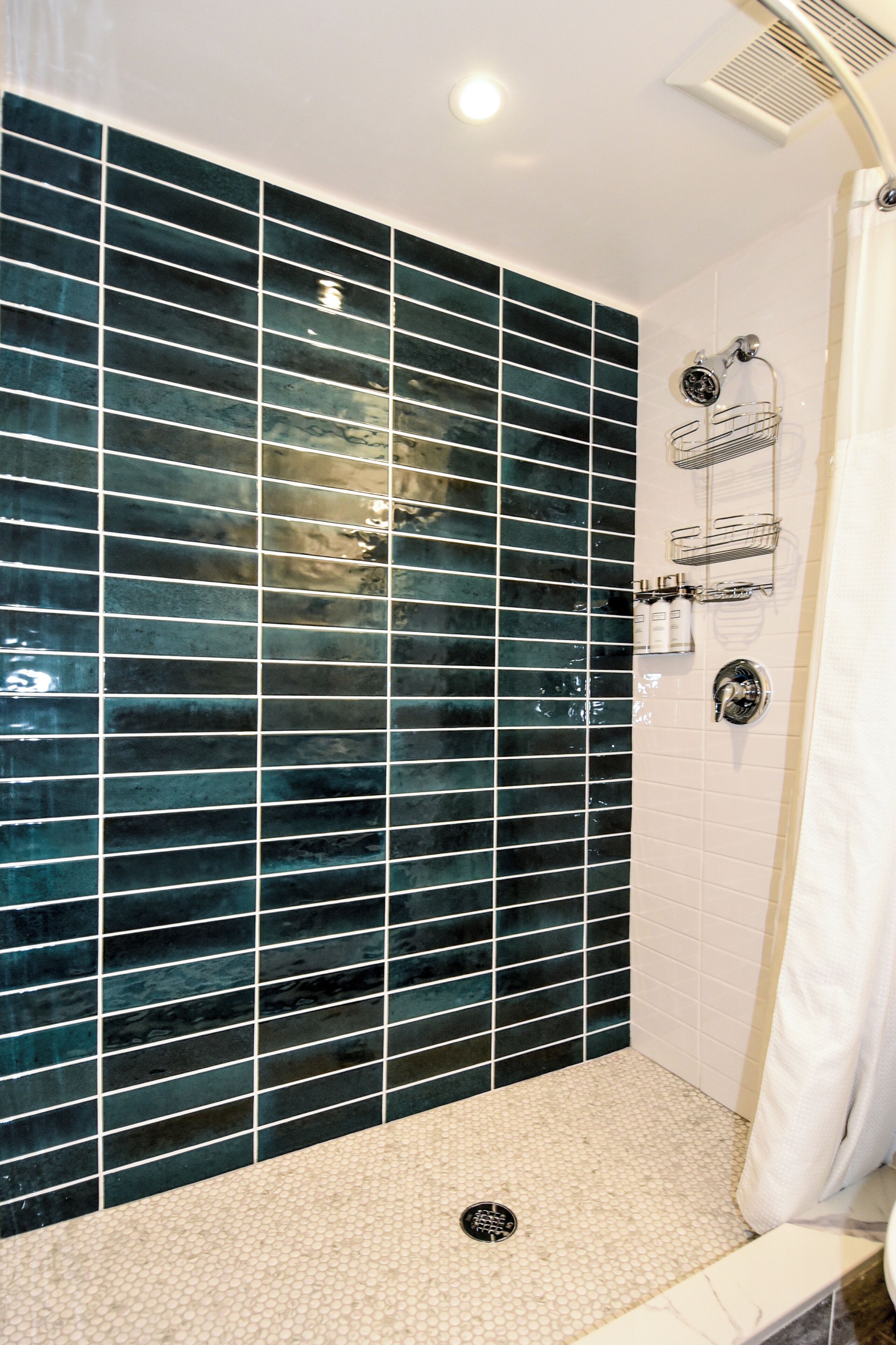 A shower with a tiled wall and a white floor.
