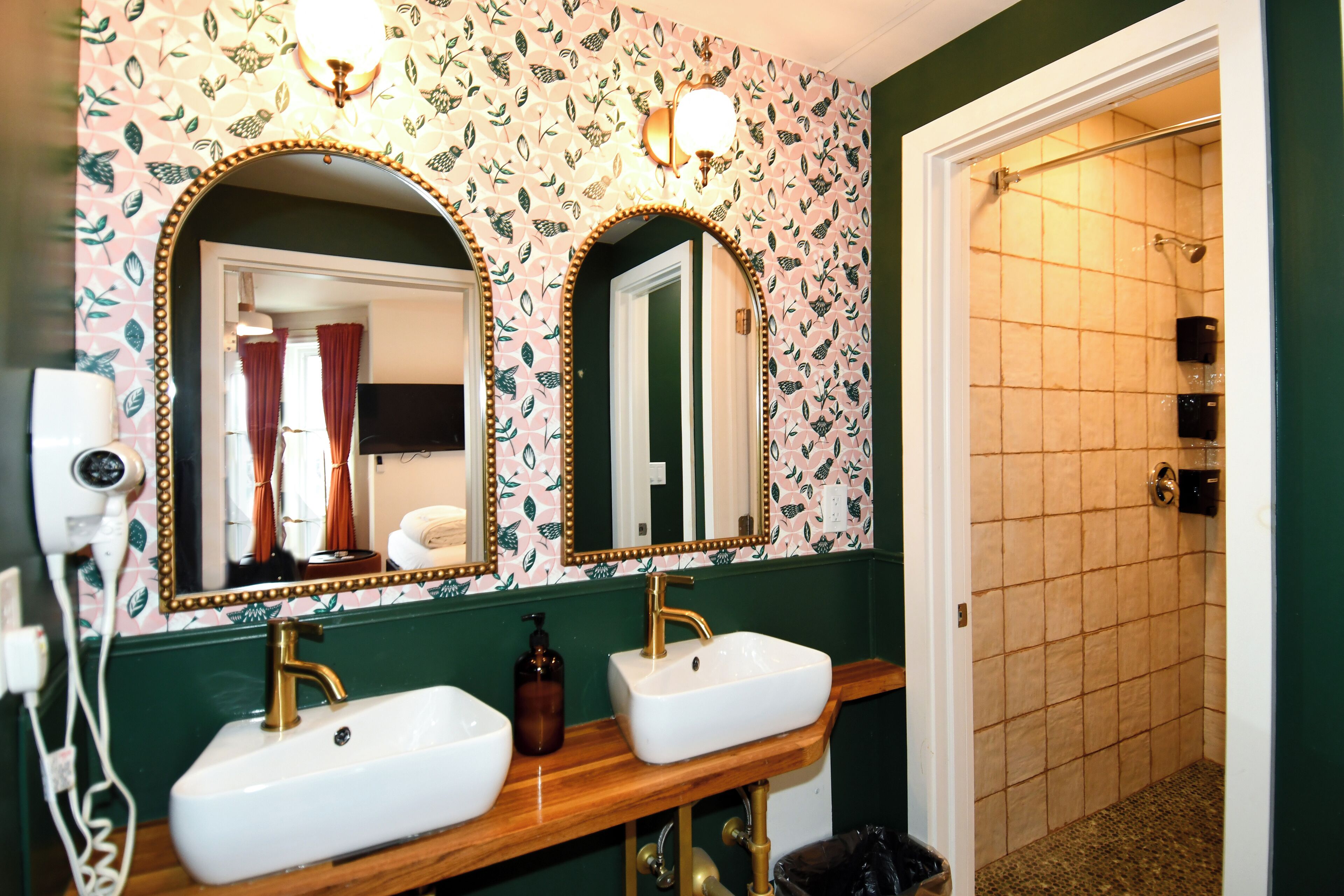 A bathroom with two sinks, a mirror, and a shower.