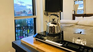 A hotel room with a large window, a bed, a TV, a kettle, and a chandelier. - HighRoad Washington DC (Washington)