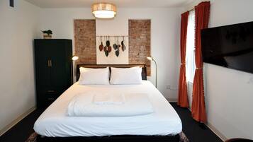 A neatly made bed with white linens, a dark wooden headboard, and a hanging light fixture above.