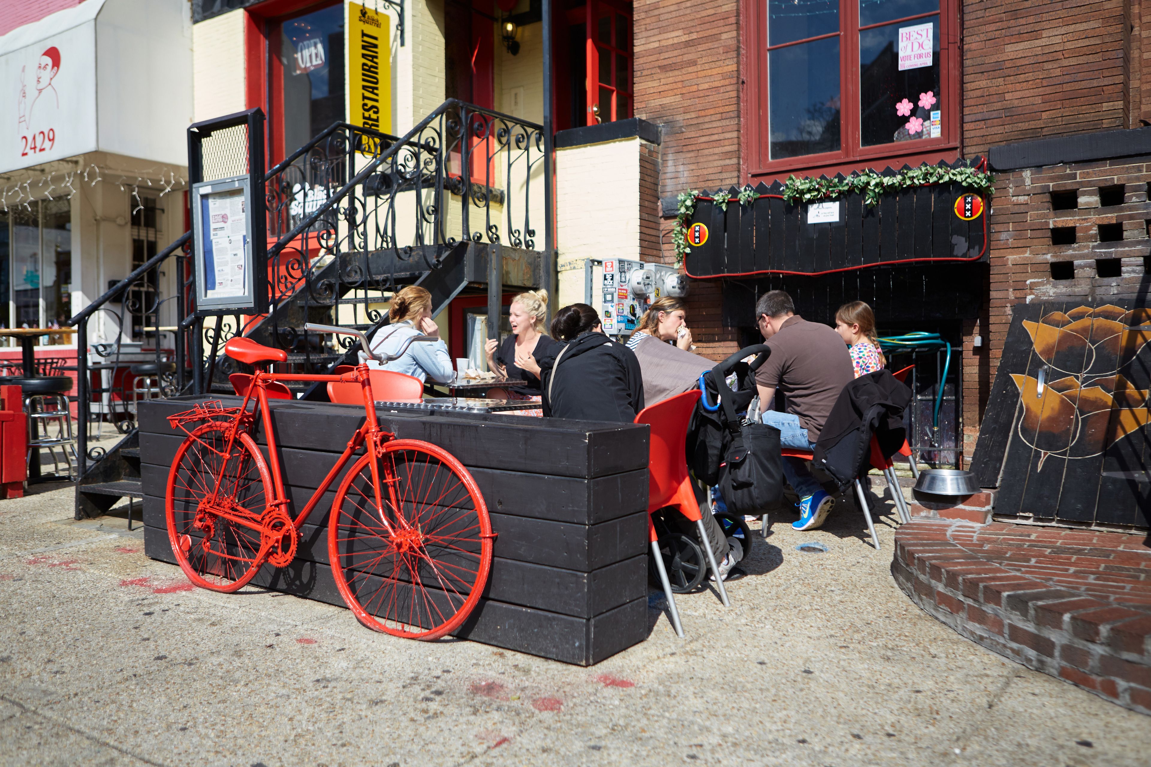 Un ristorante con posti a sedere all'aperto, una bicicletta rossa e un muro in mattoni.