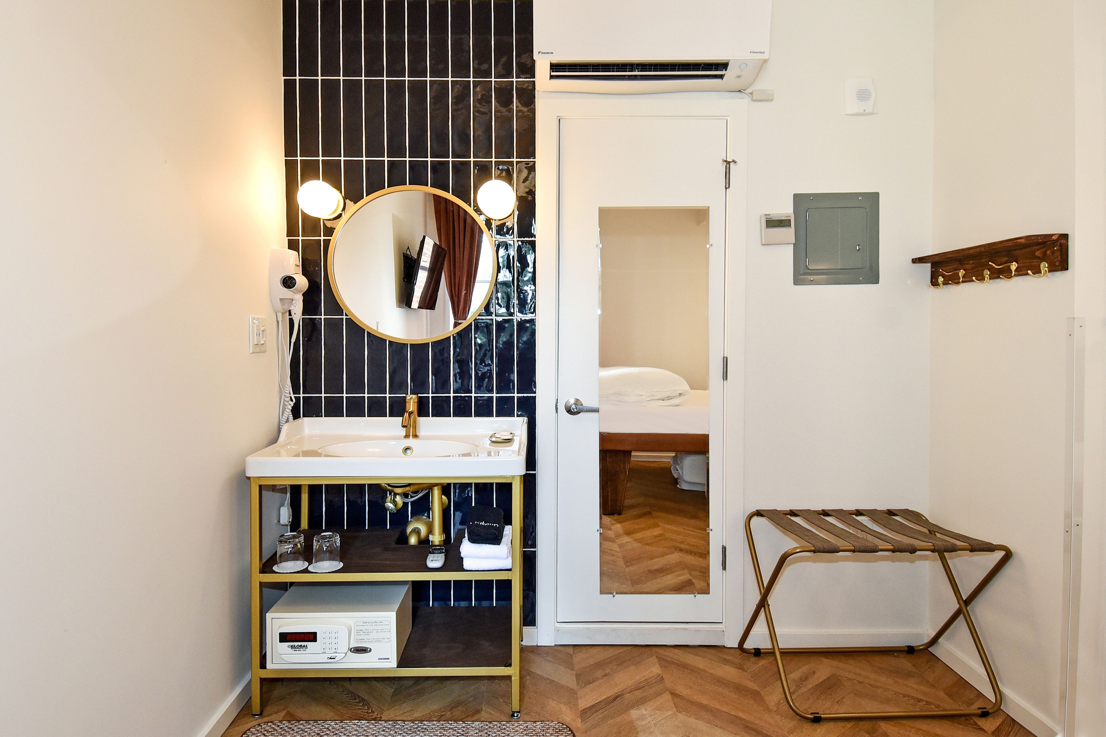 Un baño con un lavabo blanco, un espejo con iluminación, un calentador y un perchero para toallas.