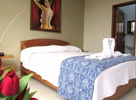 Una habitación de hotel con una cama, un cuadro en la pared y una rosa roja en el suelo.