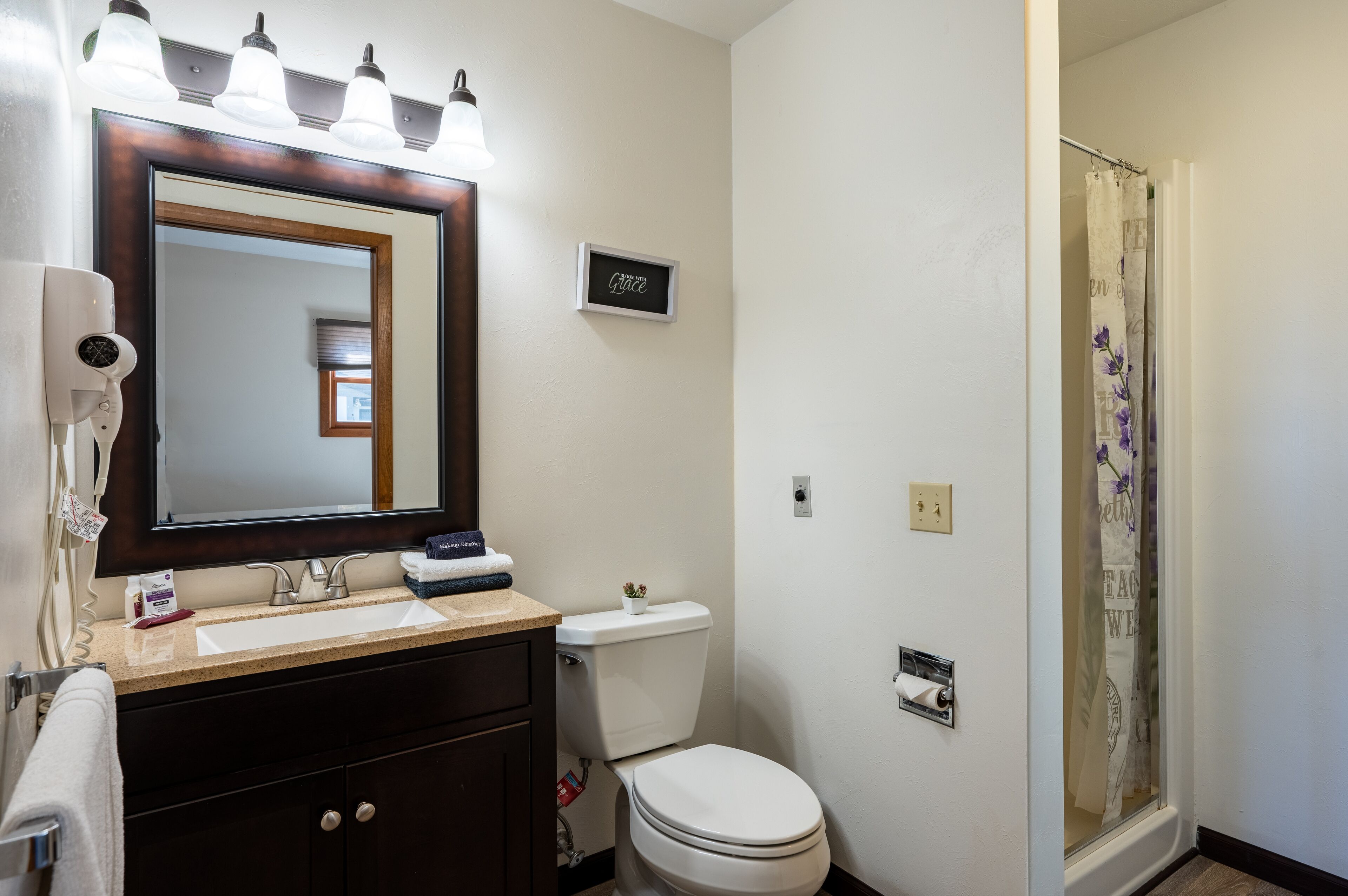Un baño con lavamanos doble, inodoro y ducha con puerta de cristal.