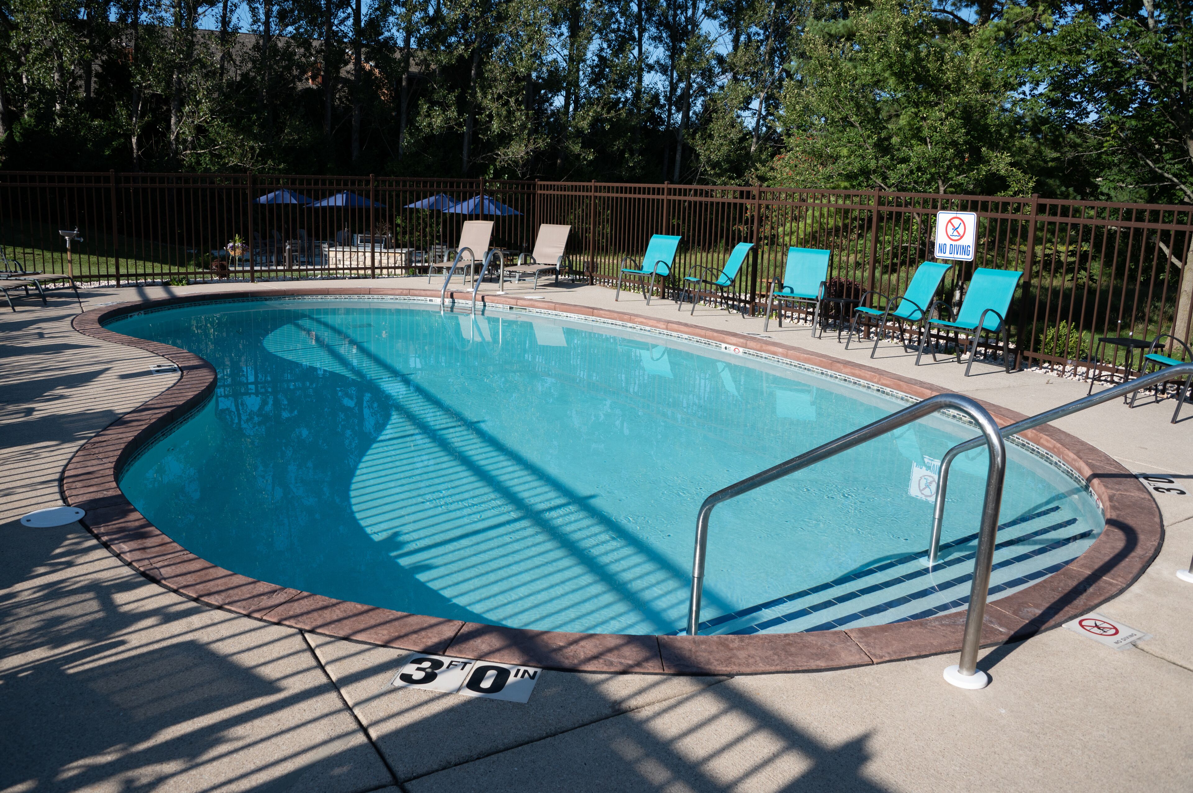 Una piscina al aire libre, sillones reclinables de piscina