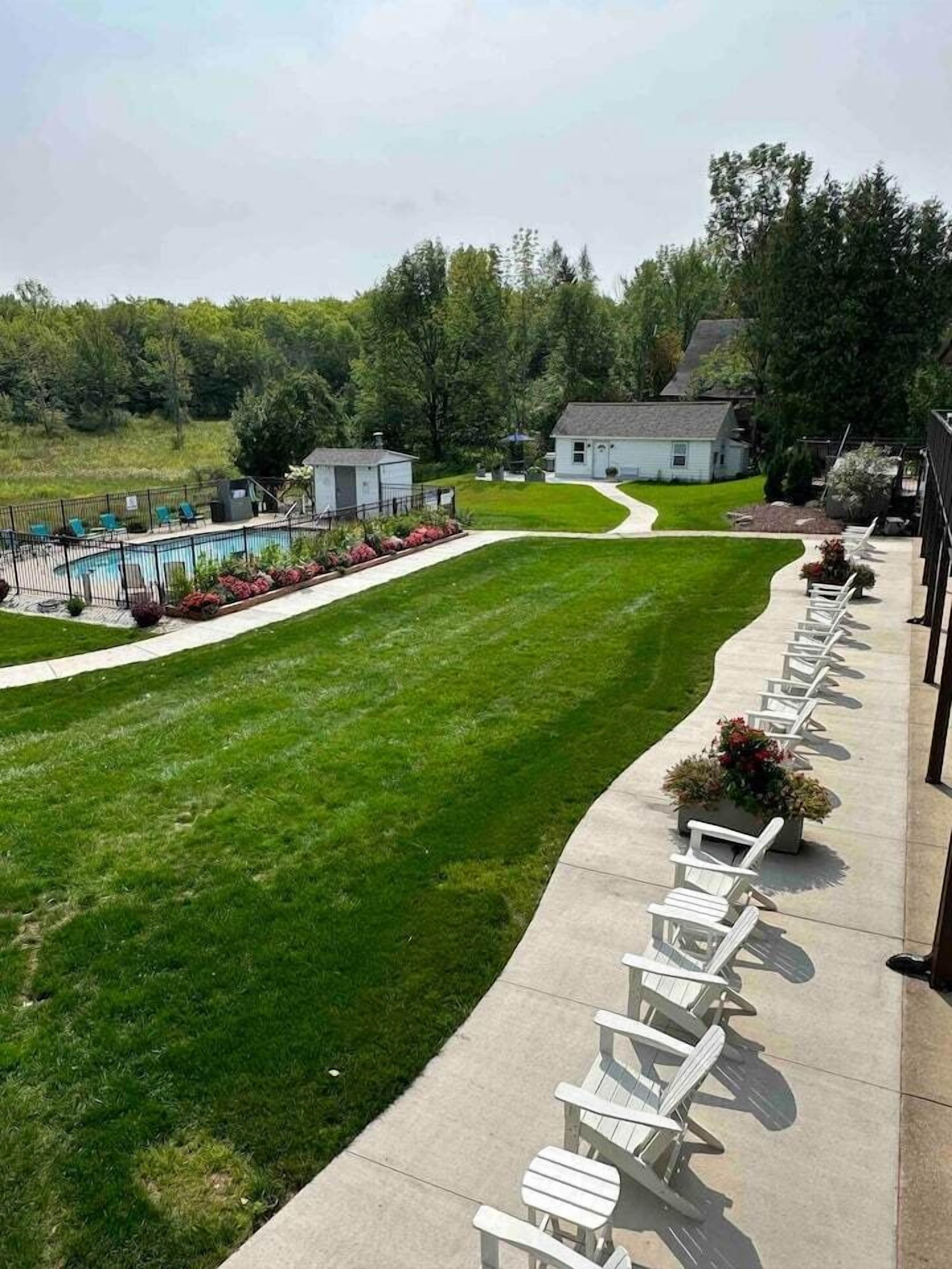 A well-maintained lawn with a pool and lounge chairs along a pathway.