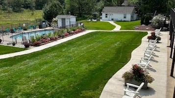 A well-maintained lawn with a pool and lounge chairs along a pathway.