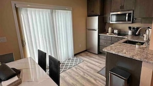 A compact kitchen with a microwave, refrigerator, and sink. There's a dining area with a table and chairs. - Sister Bay Inn (Sister Bay)