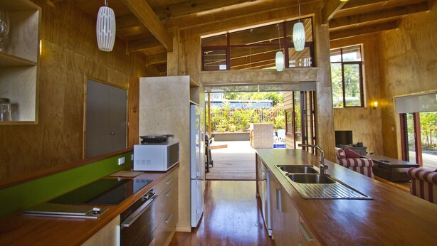 Uma cozinha moderna com armários de madeira, uma pia de aço inoxidável e um espaço de refeições com mesa e cadeiras.