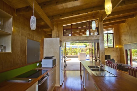 A modern kitchen with wooden cabinetry, a stainless steel sink, and a dining area with a table and chairs.