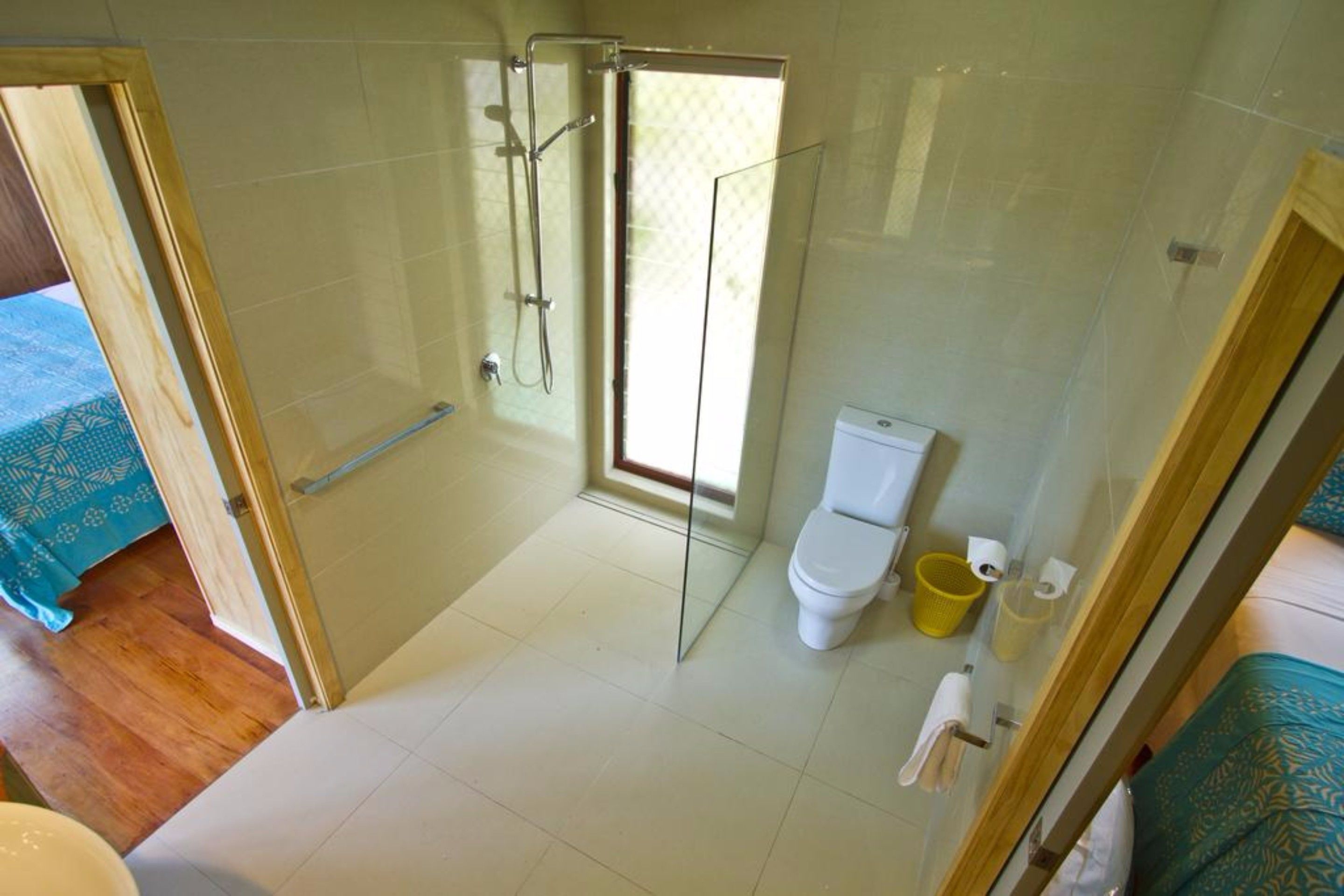 A bathroom with a glass shower enclosure, a toilet, and a sink.