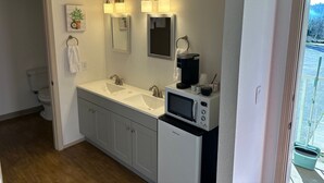 A bathroom with a double sink, a toilet, a mirror, and a coffee maker. - Brownsville Motel (Brownsville)