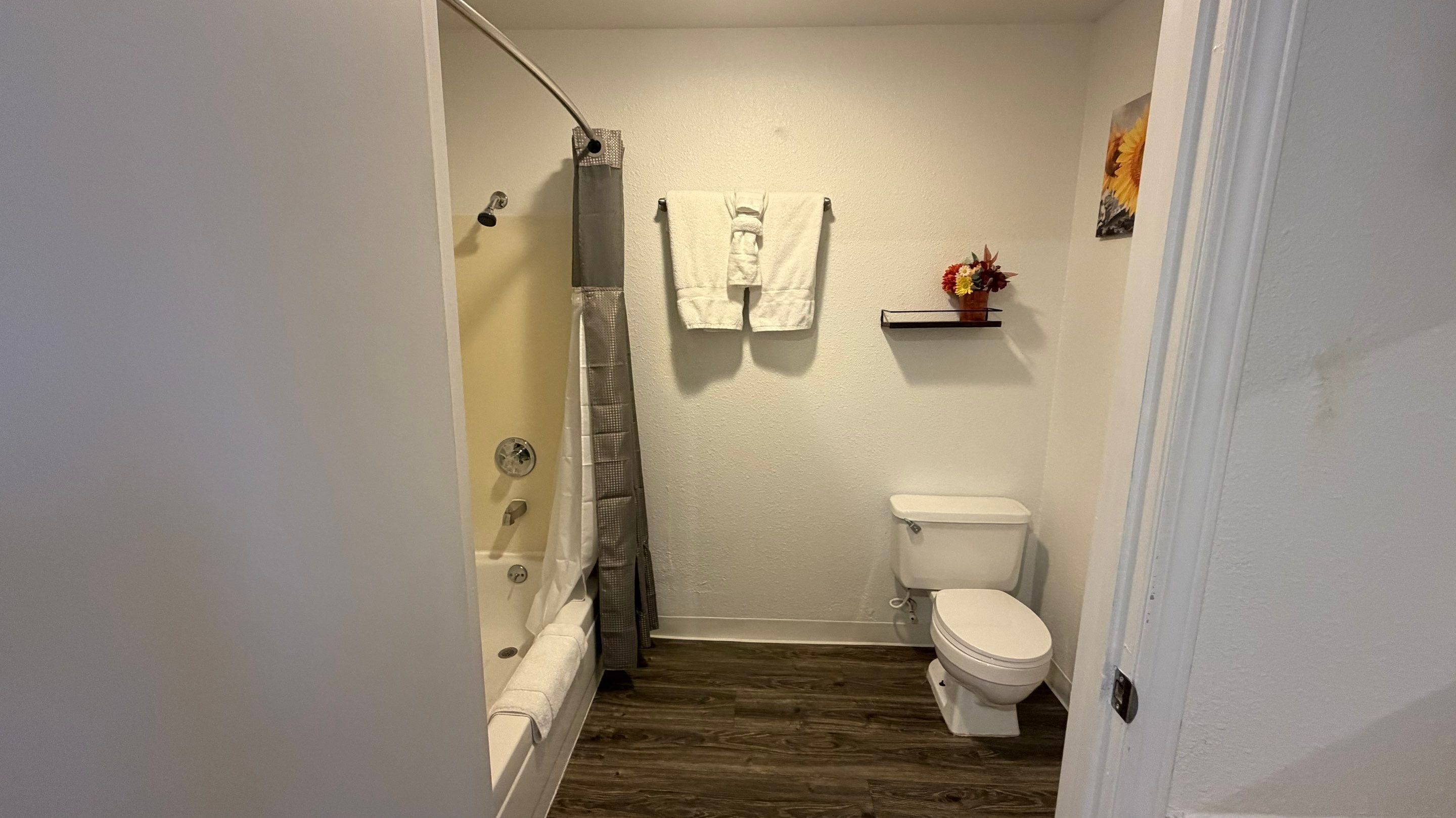 Een kleine badkamer met een douche, toilet en een handdoekhouder.